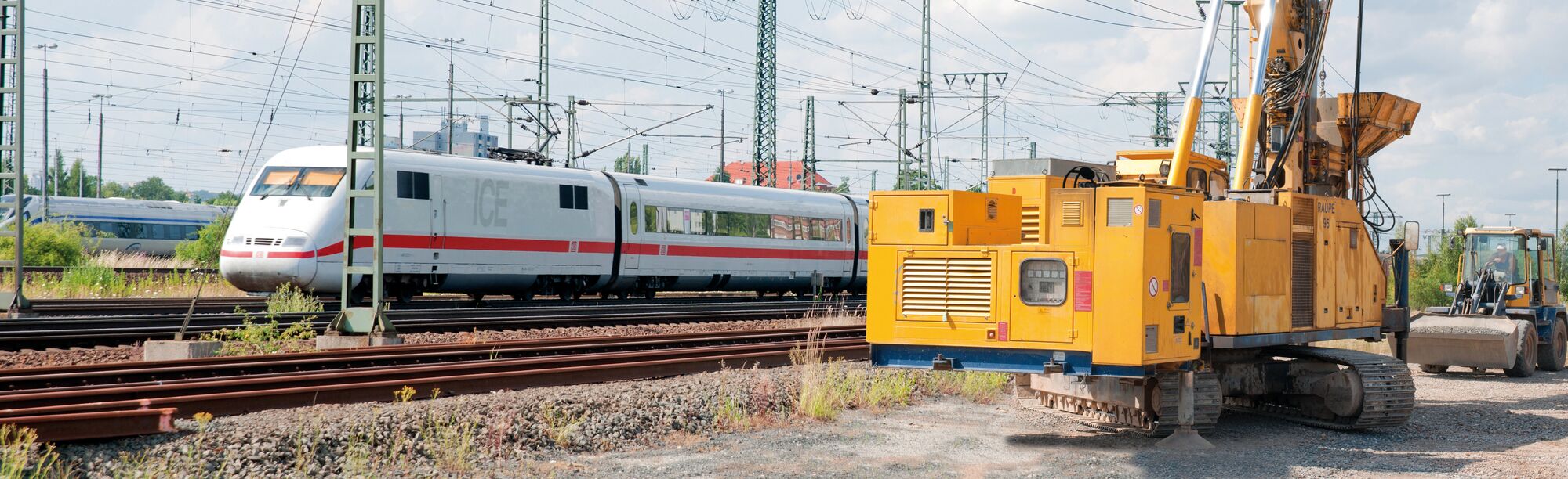 Großbaustelle mit Baumaschinen an Bahnstrecke mit ICE